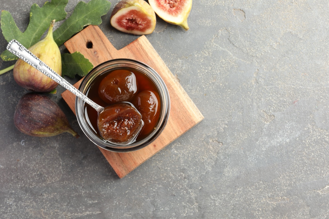 Jar of fig jam with fresh figs and a green leaf